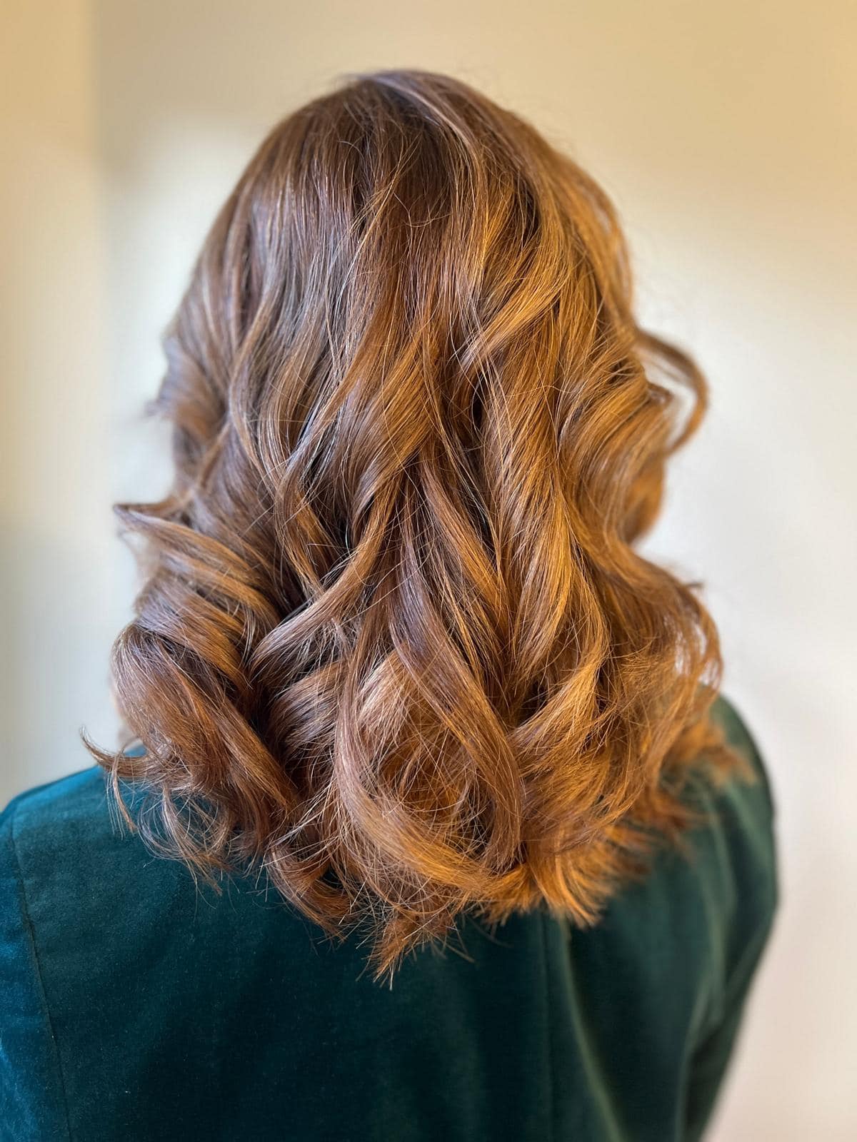 - Salone Estetica in Winchester, MA Person with medium-length, wavy, light brown hair color, wearing a dark green top, shown from the back against a plain light background. - Salone Estetica in Winchester, MA