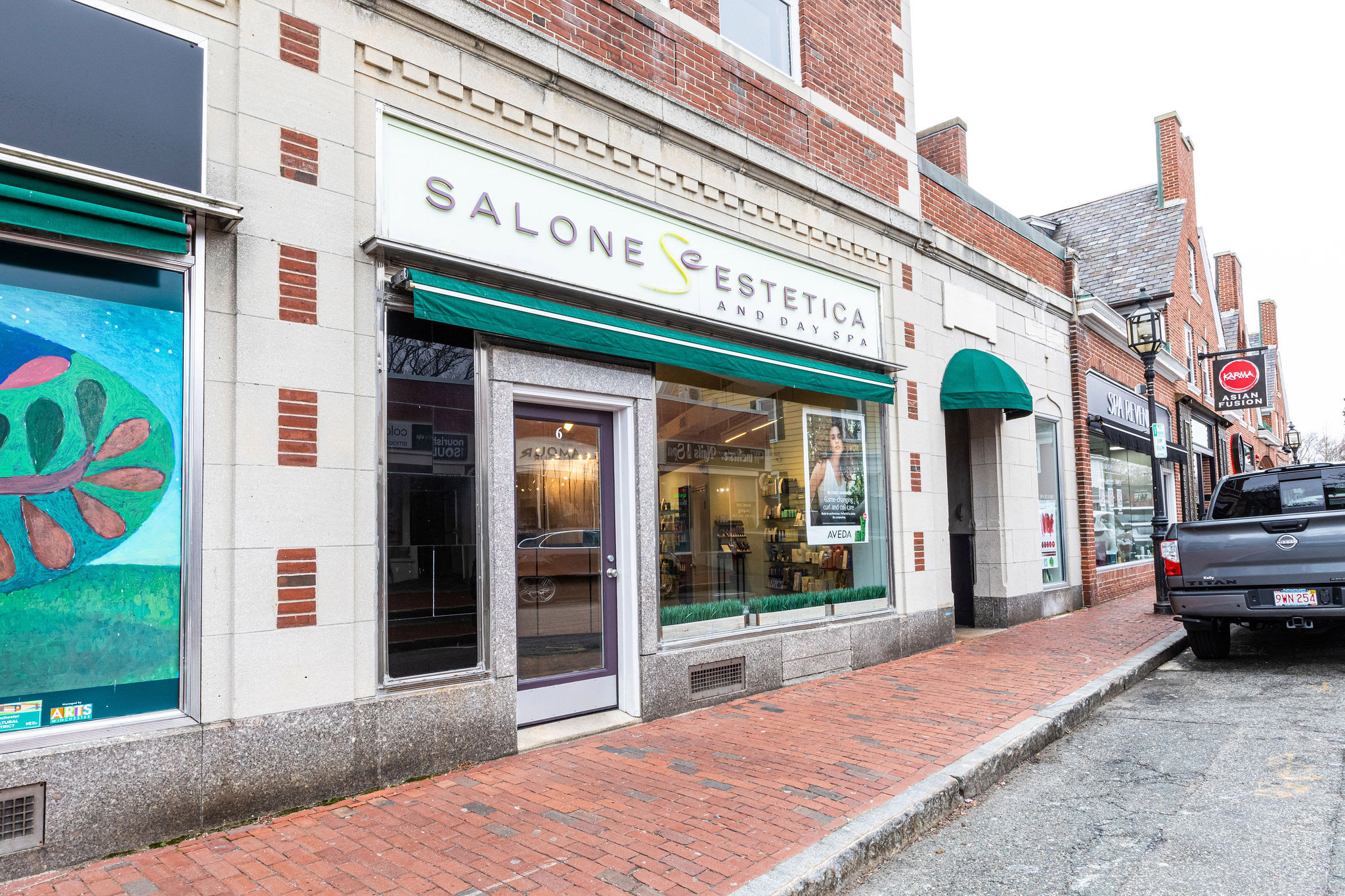 - Salone Estetica in Winchester, MA Street view of Salone Estetica and Day Spa storefront with green awnings, glass door, and a brick sidewalk—your destination for expert hair color and professional hair stylist services. - Salone Estetica in Winchester, MA