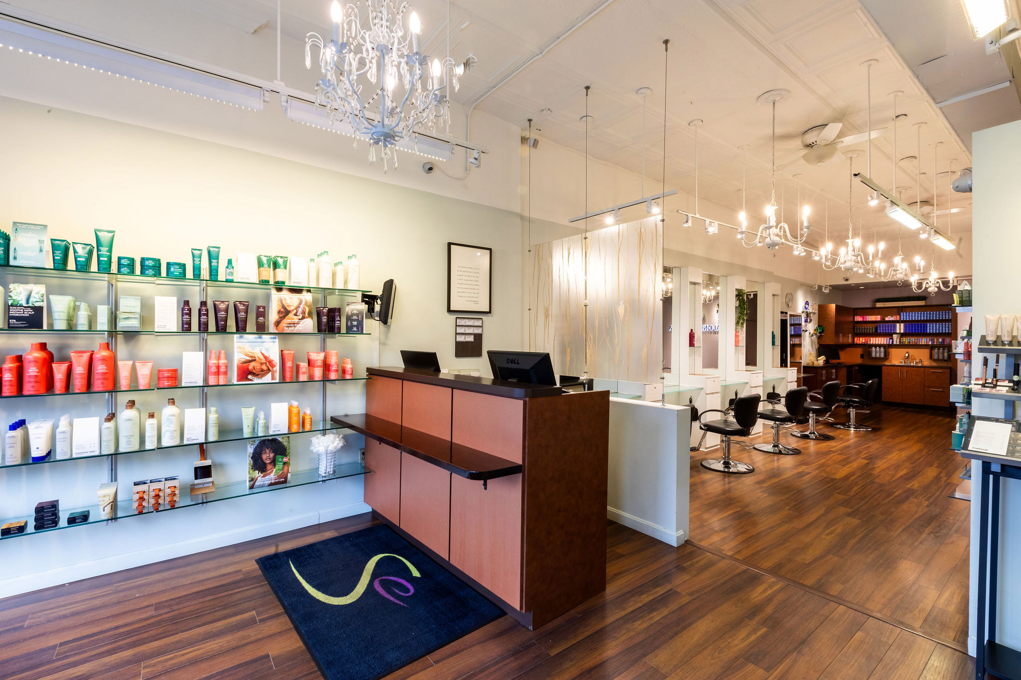 - Salone Estetica in Winchester, MA Modern Aveda salon interior with a reception desk, shelves of hair products, styling stations with chairs, and wooden flooring under bright chandeliers—perfect for wedding hair and makeup. - Salone Estetica in Winchester, MA