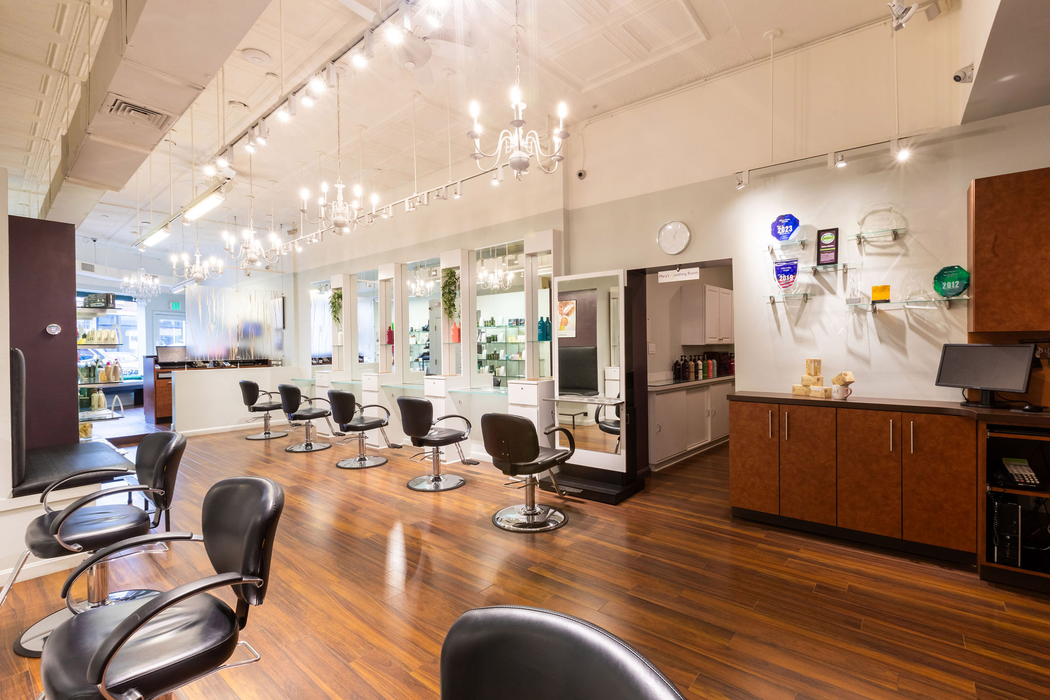 - Salone Estetica in Winchester, MA Modern Aveda salon interior with empty black styling chairs, large mirrors, wooden floors, and bright overhead lighting. Shelves displaying hair color products and awards highlight why it's considered the best salon. - Salone Estetica in Winchester, MA
