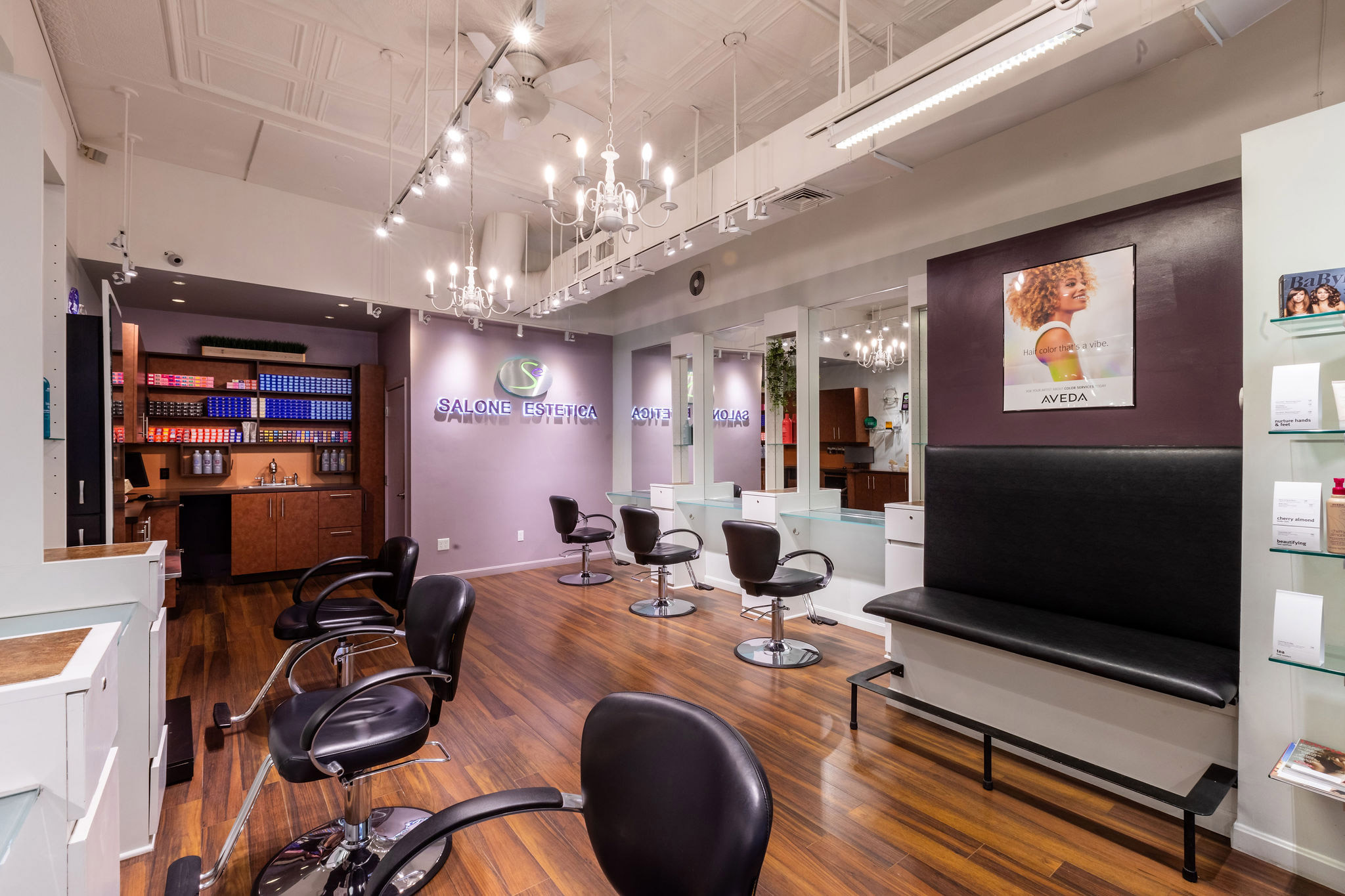 - Salone Estetica in Winchester, MA A modern hair salon interior with black chairs, white stations, wooden floors, and product shelves—expert hair stylists provide the best salon experience, all beautifully lit by ceiling lights and chandeliers. - Salone Estetica in Winchester, MA